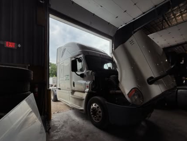 Freightliner Cascadia with the hood tilted open inside the Best Way service bay