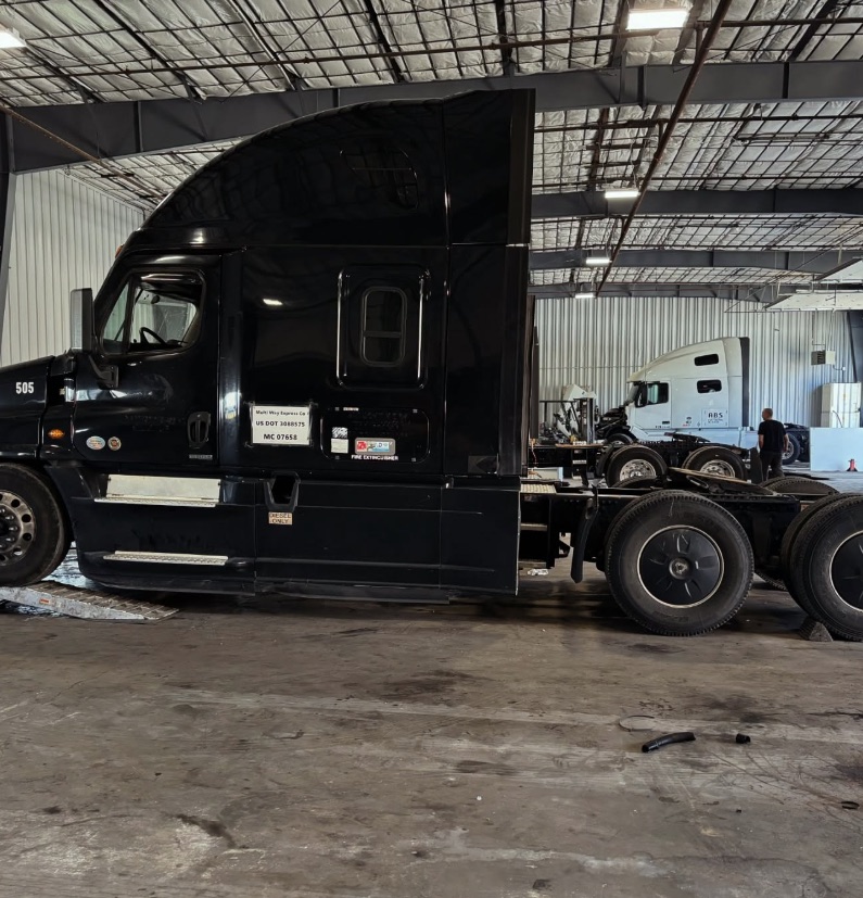 Black Freightliner Cascadia tractor in the Best Way service bay