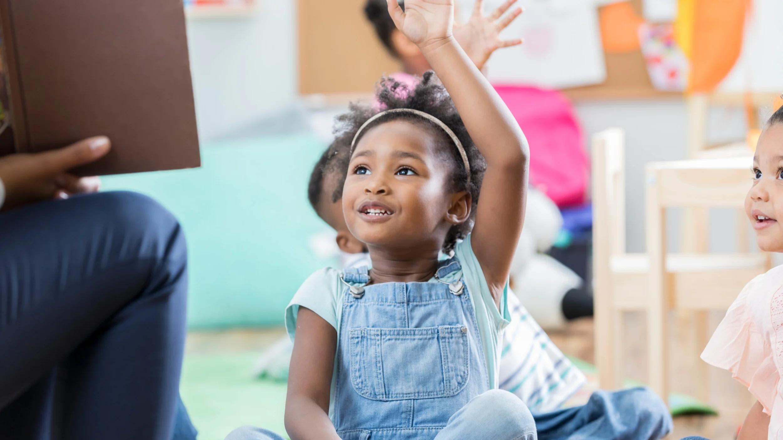 A preschooler eagerly raising her hand during circle time