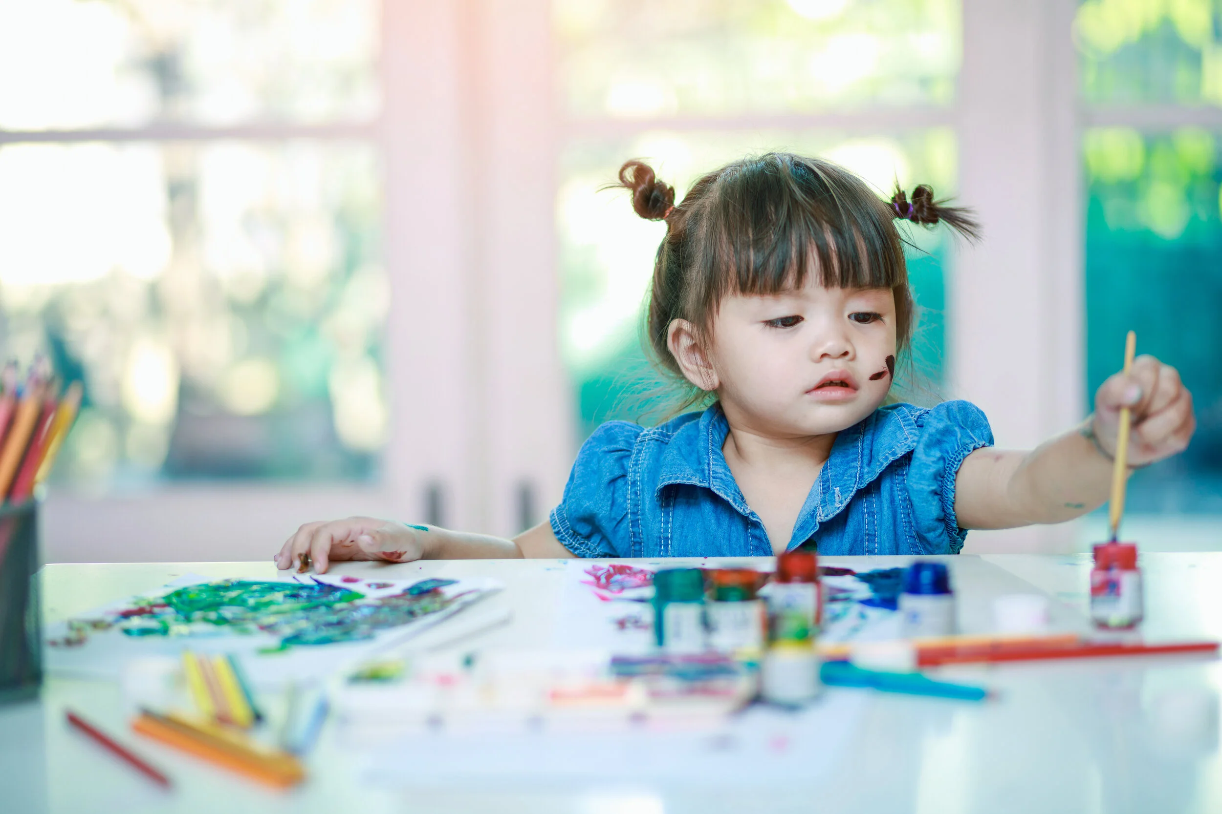 A toddler girl painting at a table