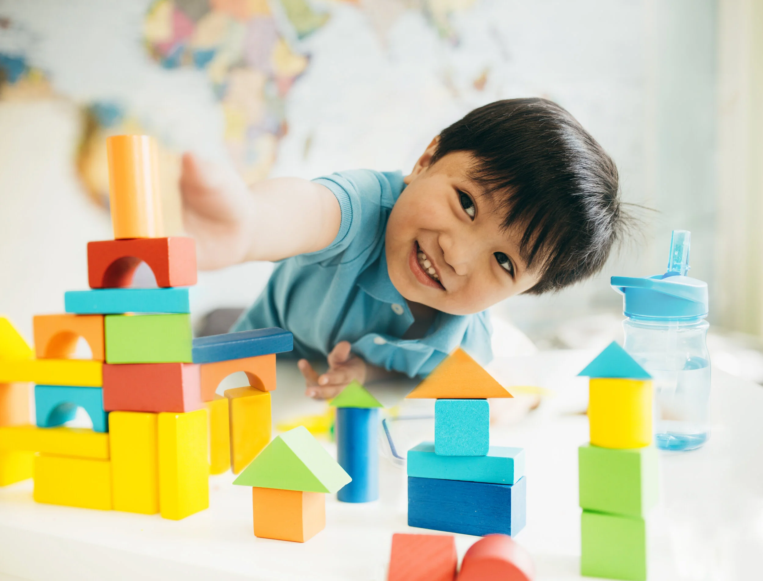 A young boy smiling while building with colorful blocks