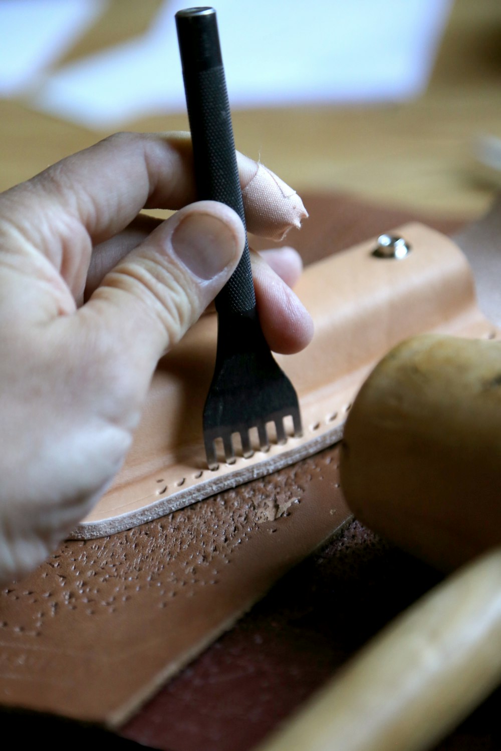 Hands tooling leather at the workbench