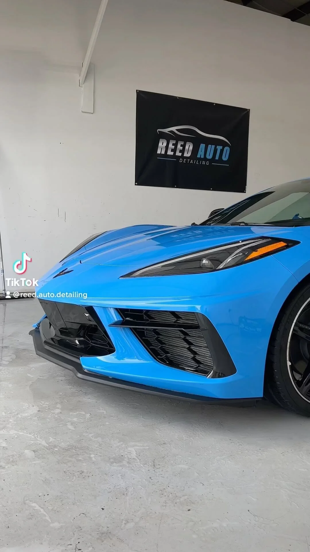 Blue Corvette C8 front end in front of the Reed Auto banner